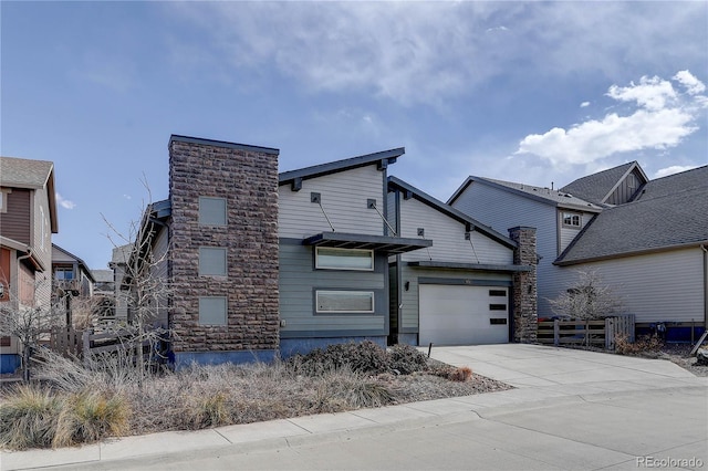 view of front of house with stone siding, an attached garage, and concrete driveway