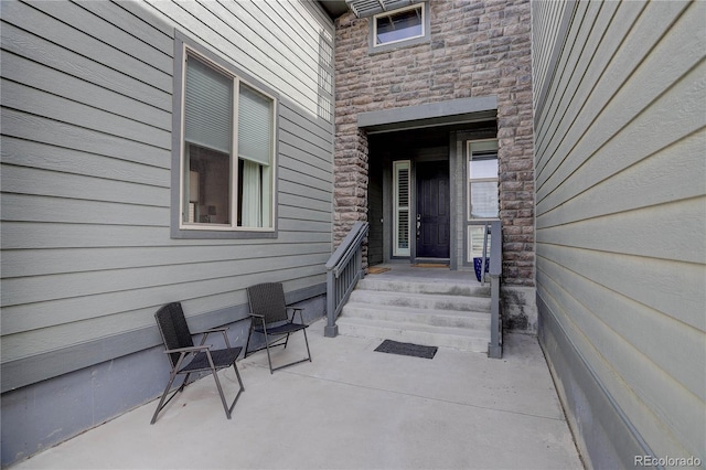 doorway to property featuring stone siding and a patio area