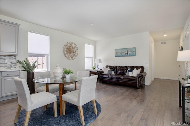 dining room featuring plenty of natural light, baseboards, light wood-type flooring, and visible vents