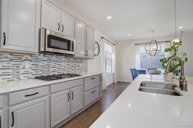 kitchen with dark wood finished floors, a sink, decorative backsplash, light countertops, and stainless steel appliances