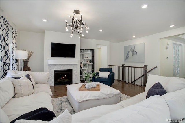 living area with recessed lighting, a warm lit fireplace, and wood finished floors