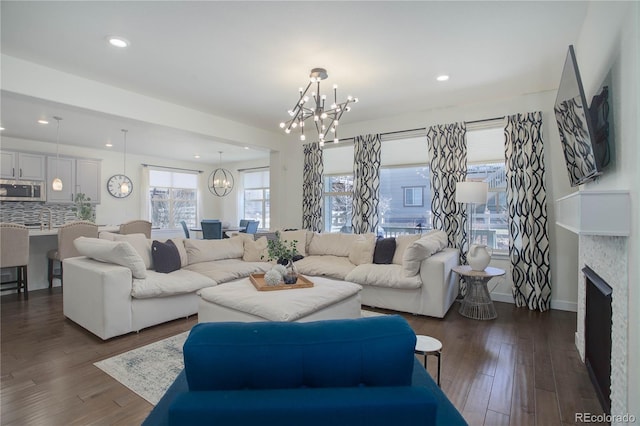 living area with baseboards, recessed lighting, a fireplace, an inviting chandelier, and dark wood-style floors