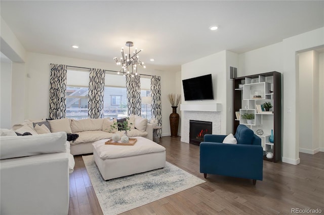 living area with a notable chandelier, recessed lighting, a warm lit fireplace, and wood finished floors