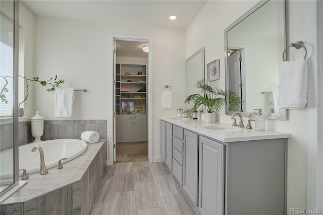 bathroom featuring double vanity, a garden tub, and a sink