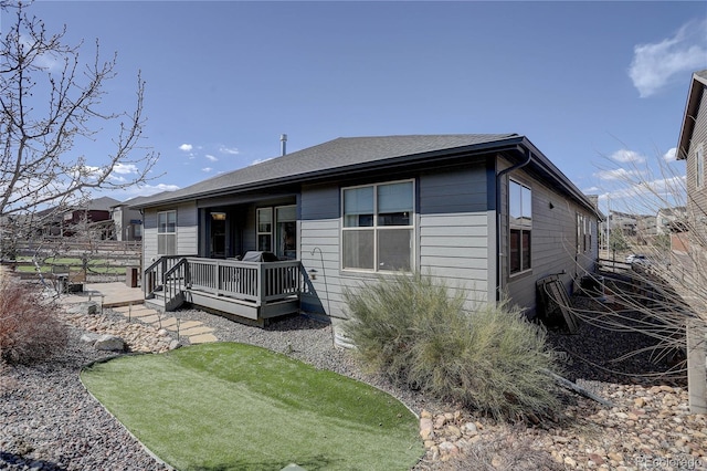 view of front of house with a wooden deck and roof with shingles