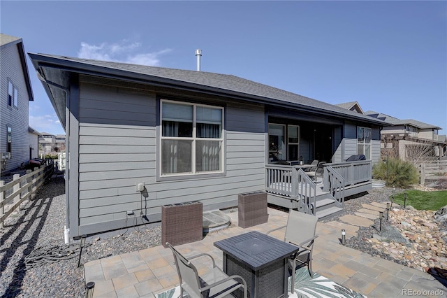 rear view of house with a deck, a patio, and fence