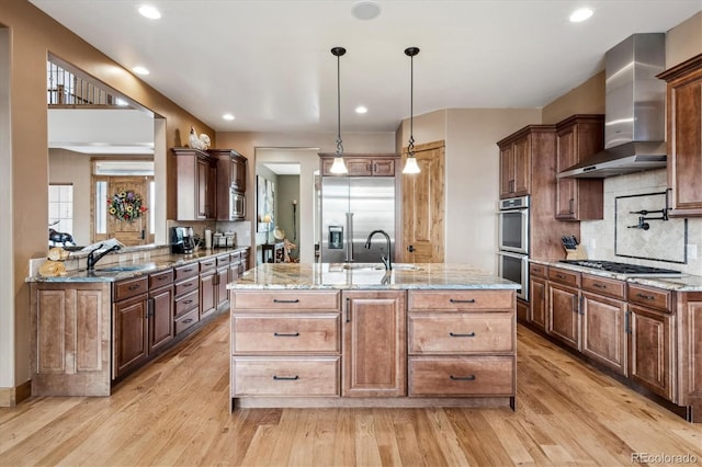 kitchen featuring sink, wall chimney range hood, built in appliances, and light hardwood / wood-style flooring