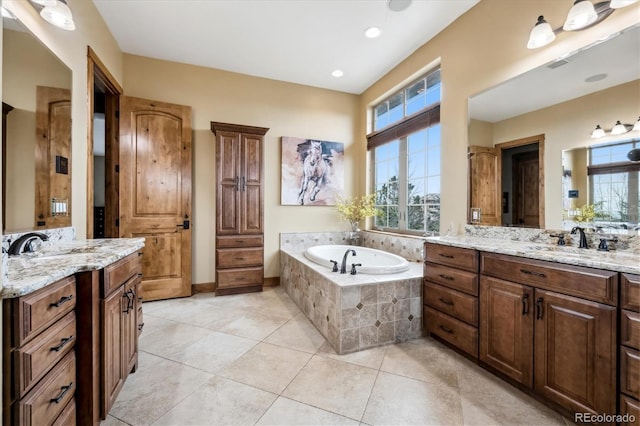 bathroom with vanity, tiled bath, and tile patterned flooring