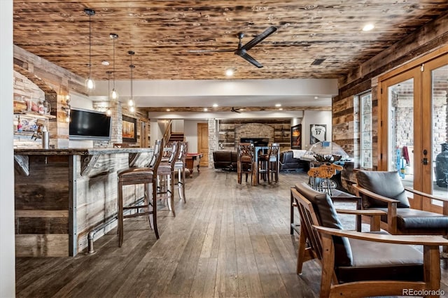 interior space with ceiling fan, hanging light fixtures, dark hardwood / wood-style floors, a large fireplace, and french doors