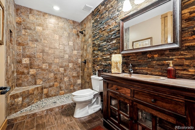 bathroom with tiled shower, vanity, and toilet