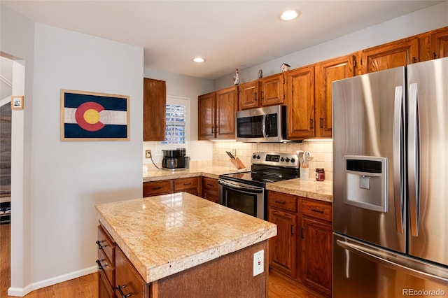 kitchen with light hardwood / wood-style floors, decorative backsplash, stainless steel appliances, and a center island