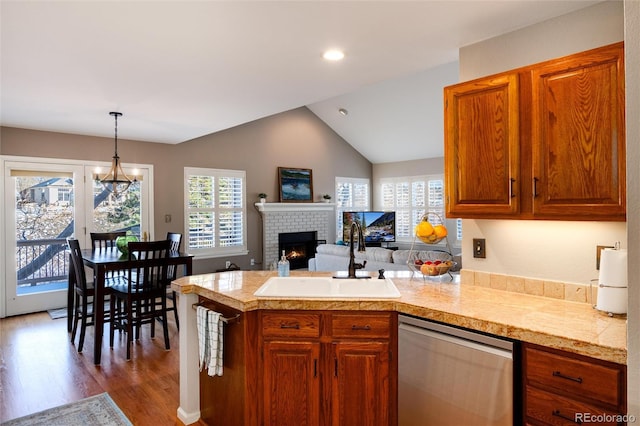 kitchen with lofted ceiling, sink, decorative light fixtures, stainless steel dishwasher, and hardwood / wood-style floors