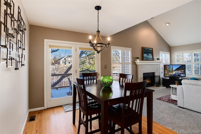 dining space with a wealth of natural light, a notable chandelier, light hardwood / wood-style floors, and a fireplace