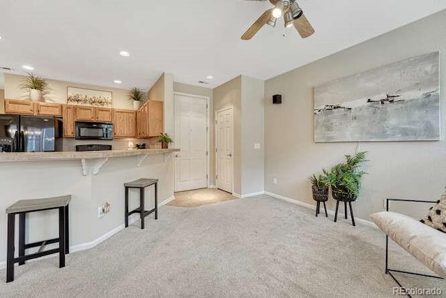 17225 Lark Water Ln Unit C, Parker, CO 80134 - kitchen with black appliances, a breakfast bar area, light carpet, ceiling fan, and light countertops