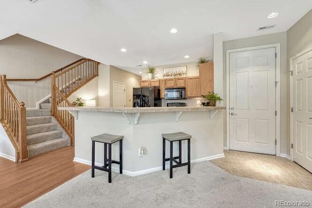17225 Lark Water Ln Unit C, Parker, CO 80134 - kitchen with black appliances, a breakfast bar, recessed lighting, light countertops, and light carpet