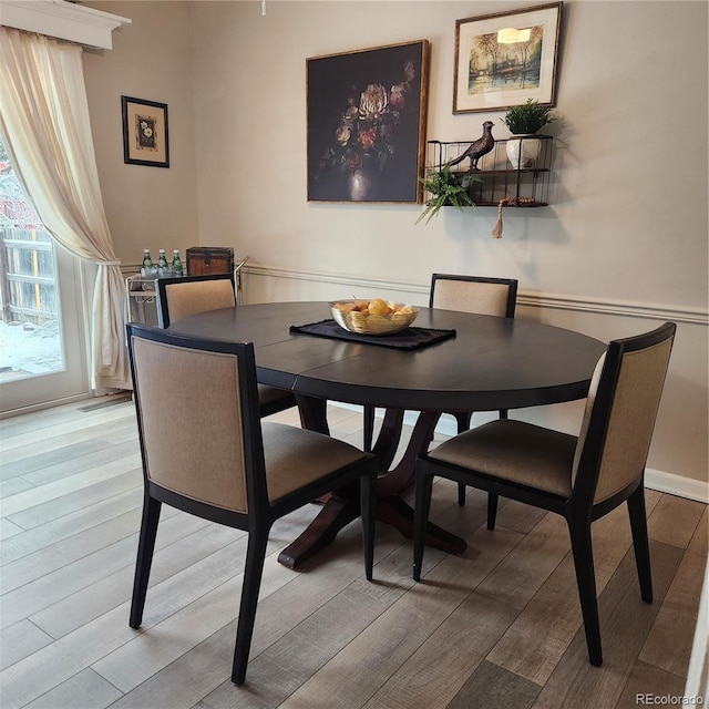 dining area with light wood finished floors and baseboards