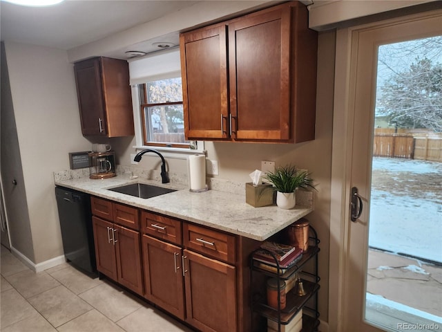 kitchen with light tile patterned floors, baseboards, dishwasher, light stone countertops, and a sink