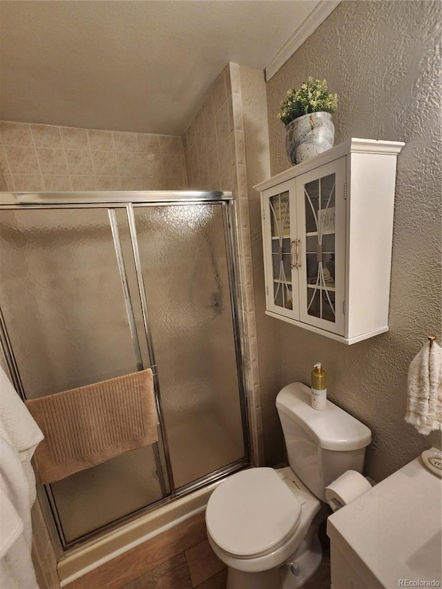 bathroom featuring toilet, a shower stall, and a textured wall