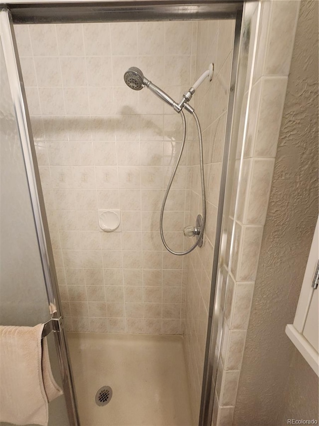 full bathroom with a textured wall and a shower stall