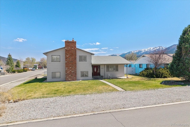 view of front of home with a mountain view, a front yard, and a chimney