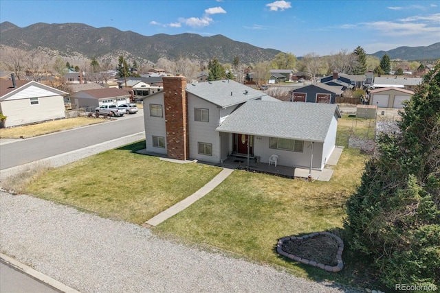 view of front of property featuring covered porch, roof with shingles, a residential view, a mountain view, and a front lawn
