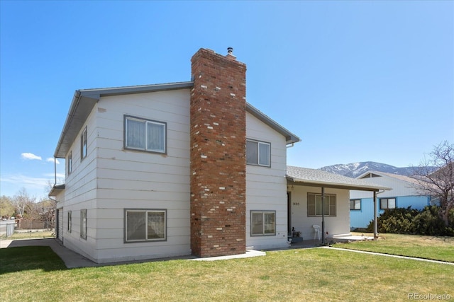 back of property with a chimney and a yard