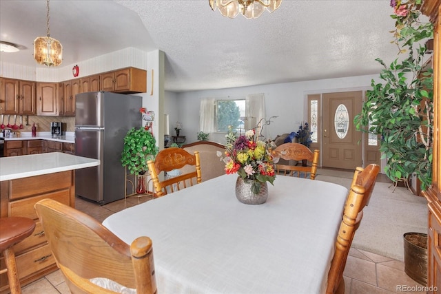 dining room with a textured ceiling, light tile patterned floors, and a notable chandelier