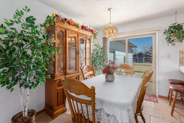 dining room with baseboards, light tile patterned flooring, a textured ceiling, and a notable chandelier