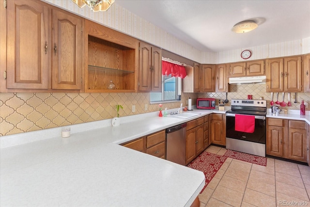 kitchen featuring brown cabinets, appliances with stainless steel finishes, a sink, light countertops, and under cabinet range hood