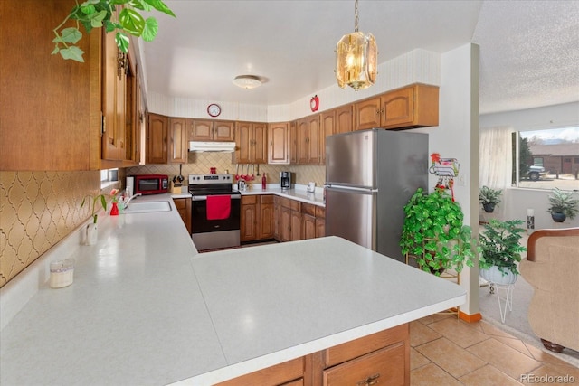 kitchen with appliances with stainless steel finishes, a sink, light countertops, brown cabinetry, and under cabinet range hood