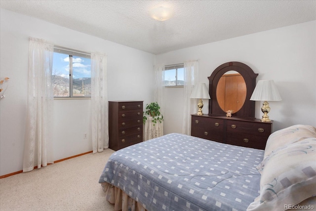 bedroom featuring a textured ceiling, baseboards, and light colored carpet