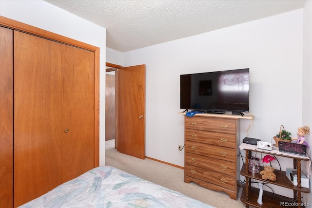 bedroom with light colored carpet, a textured ceiling, and a closet