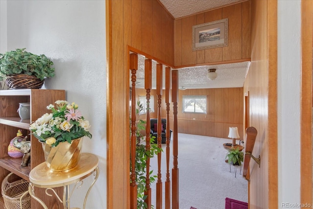 interior space with carpet floors, a textured ceiling, and wooden walls
