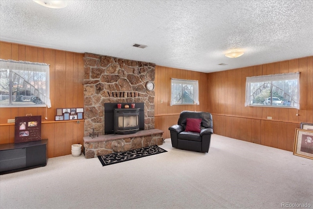 carpeted living area featuring wood walls, a textured ceiling, and visible vents