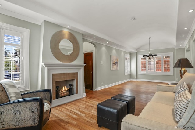 living room featuring light hardwood / wood-style flooring, a fireplace, vaulted ceiling, and an inviting chandelier