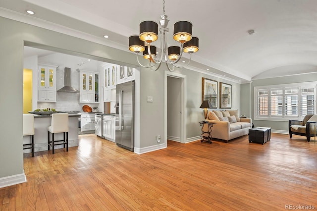 living room with lofted ceiling, light wood-type flooring, and an inviting chandelier