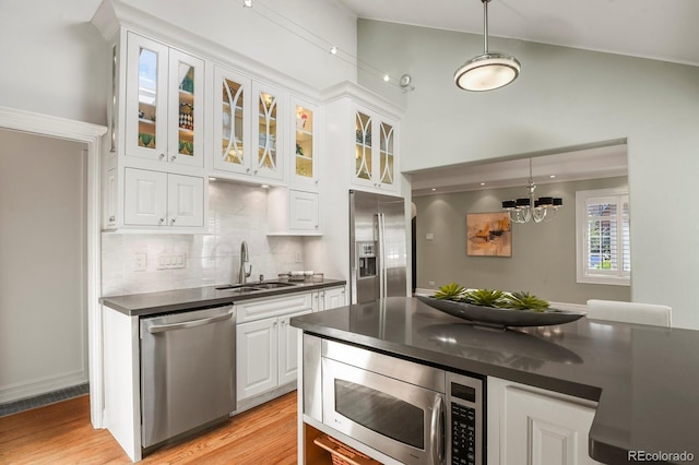 kitchen featuring sink, light hardwood / wood-style flooring, appliances with stainless steel finishes, white cabinets, and decorative light fixtures