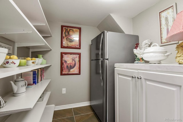 interior space with white cabinets, stainless steel fridge, and dark tile patterned flooring