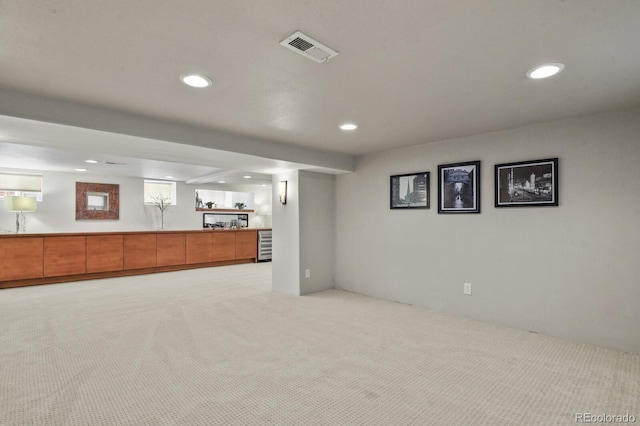 basement featuring a wealth of natural light, light colored carpet, and beverage cooler