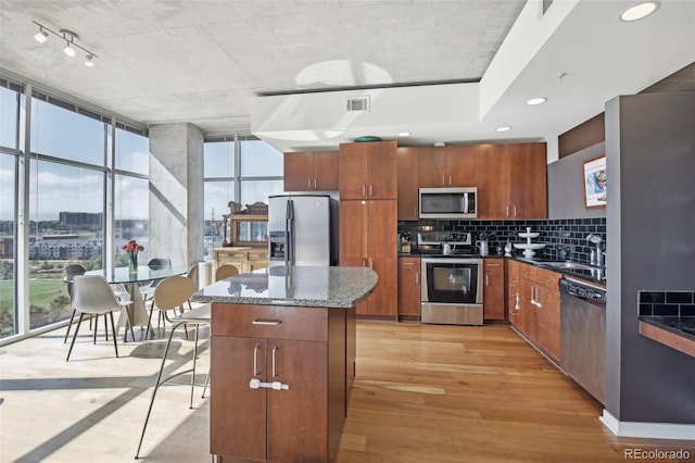 kitchen featuring sink, decorative backsplash, a center island, stainless steel appliances, and light hardwood / wood-style flooring