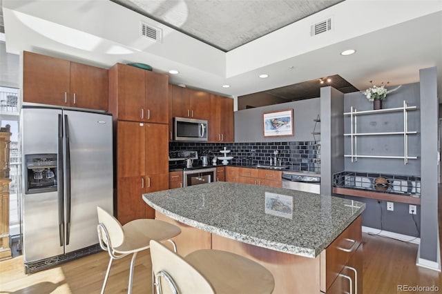 kitchen with sink, appliances with stainless steel finishes, a center island, tasteful backsplash, and dark hardwood / wood-style flooring