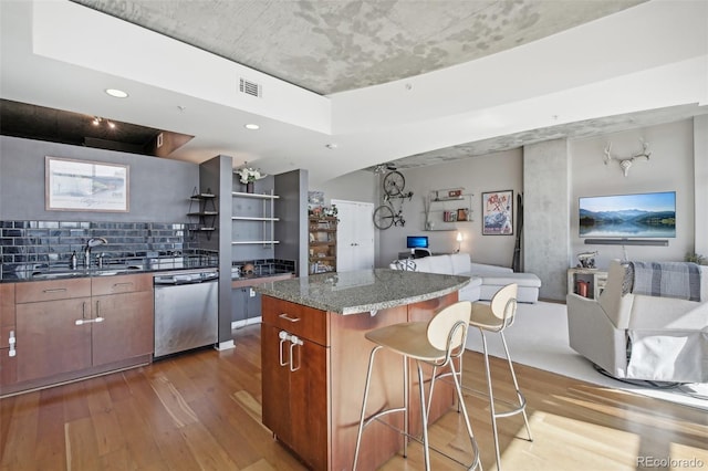 kitchen featuring a kitchen island, tasteful backsplash, sink, hardwood / wood-style flooring, and stainless steel dishwasher