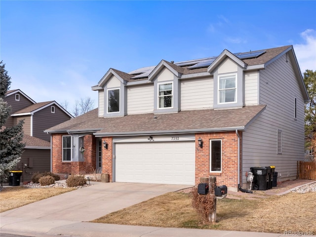 traditional home with driveway, brick siding, an attached garage, and a shingled roof