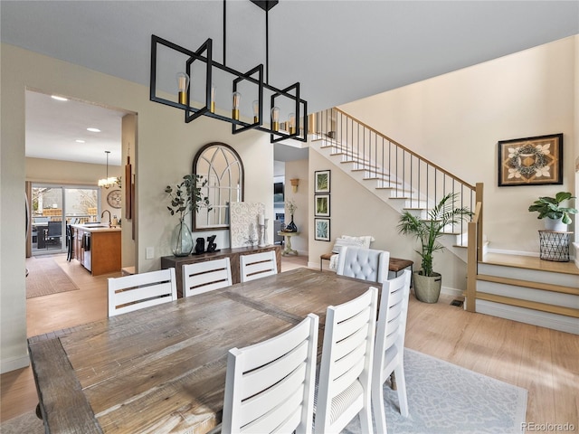 dining area with light wood-style floors, baseboards, stairs, and a chandelier