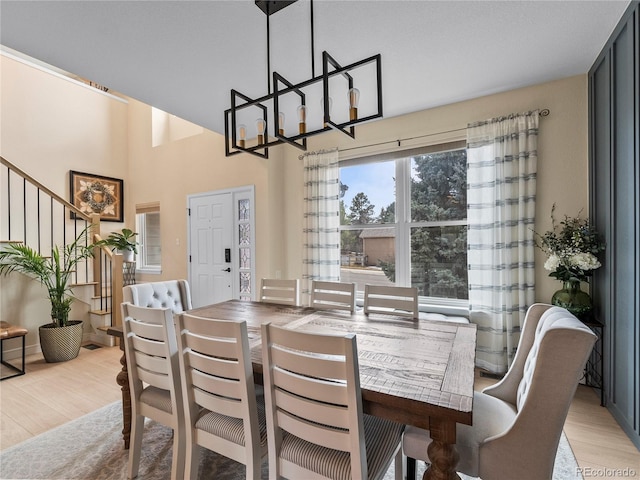 dining room with stairway, light wood-style flooring, and an inviting chandelier