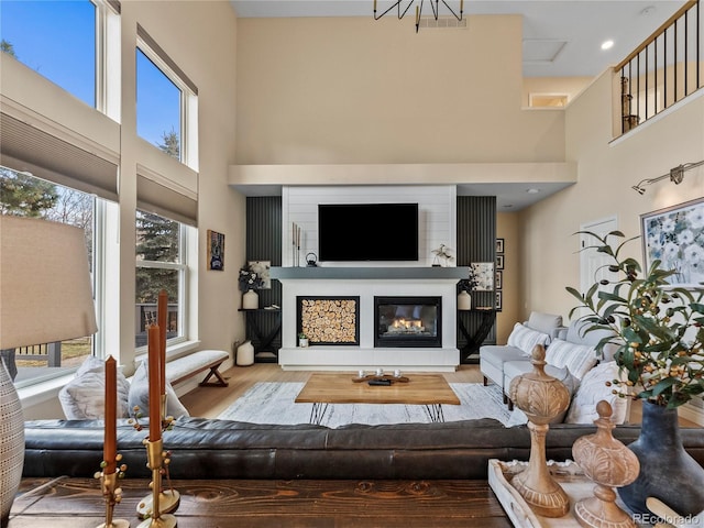 living area with a glass covered fireplace, a high ceiling, and wood finished floors