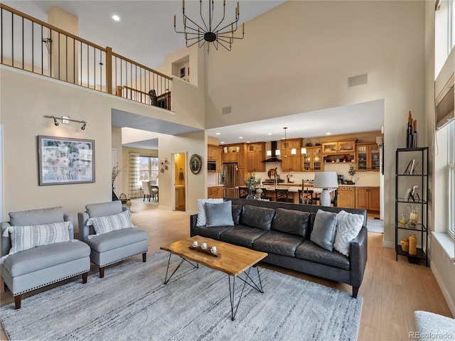 living area with recessed lighting, visible vents, baseboards, light wood-type flooring, and an inviting chandelier