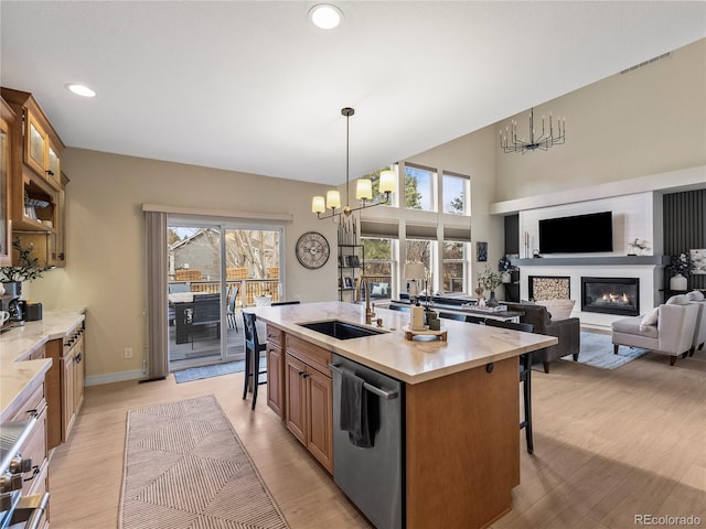 kitchen featuring dishwasher, a sink, a glass covered fireplace, and a kitchen breakfast bar