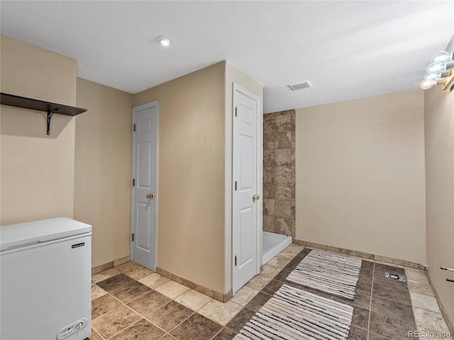 full bath with visible vents, baseboards, and tiled shower