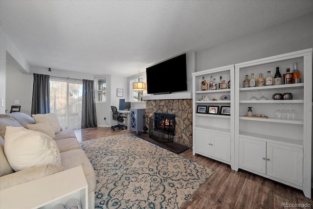 living room featuring a stone fireplace, a textured ceiling, and dark wood-type flooring